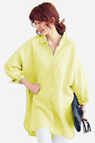 Woman wearing oversized linen shirt in light yellow with long sleeves and button-down front