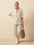 Woman wearing oversized 100% cotton shirt and wide-leg pants co-ord set with natural, breathable fabric and relaxed fit carrying a woven bag