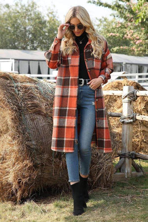 Woman wearing oversized medium-length plaid overshirt in shades of orange and brown, paired with jeans and black boots outdoors near hay bales