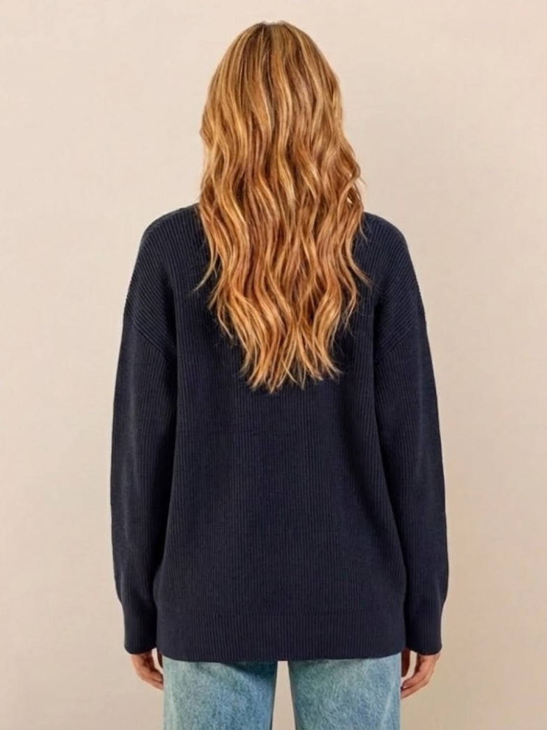 Woman wearing relaxed fit oversized navy knit cardigan from back view