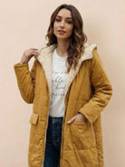 Woman wearing mustard sherpa-lined hooded teddy coat with large pockets and quilted puffer style