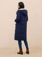 woman wearing navy sherpa-lined hooded teddy coat with long puffer silhouette and pockets