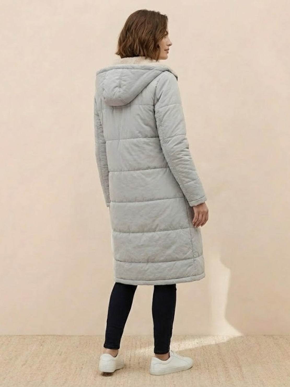 woman wearing light gray sherpa-lined hooded teddy coat with long puffer design and pockets