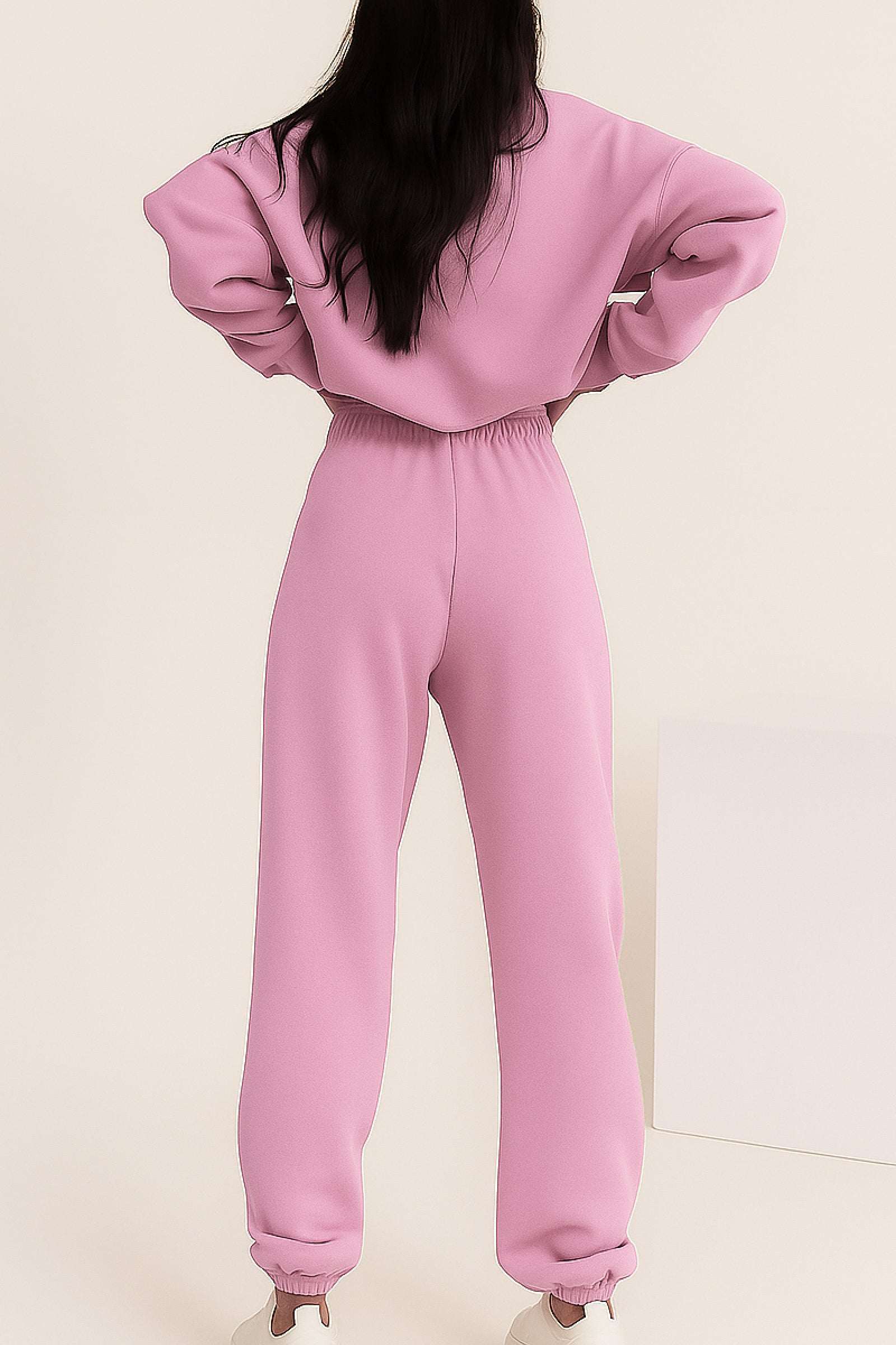Woman wearing a pink cotton blend tracksuit with cuffed pants and loose sweatshirt viewed from the back