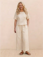 Woman wearing a loose fit co-ord set with soft-tailored top and wide-leg bottoms in solid color