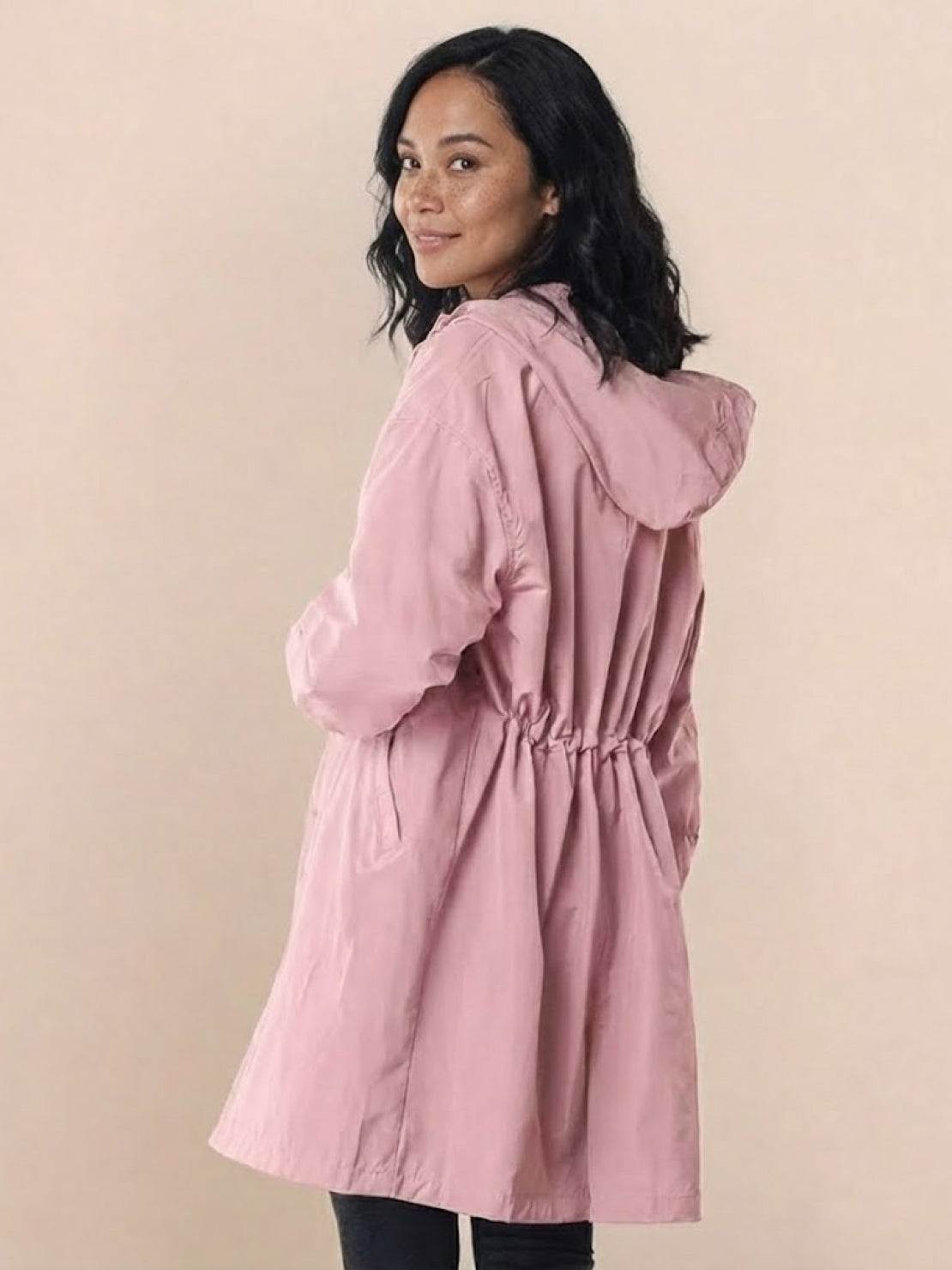 Woman wearing pink oversized Rain Couture Windbreaker jacket with adjustable hood and cinched waist.