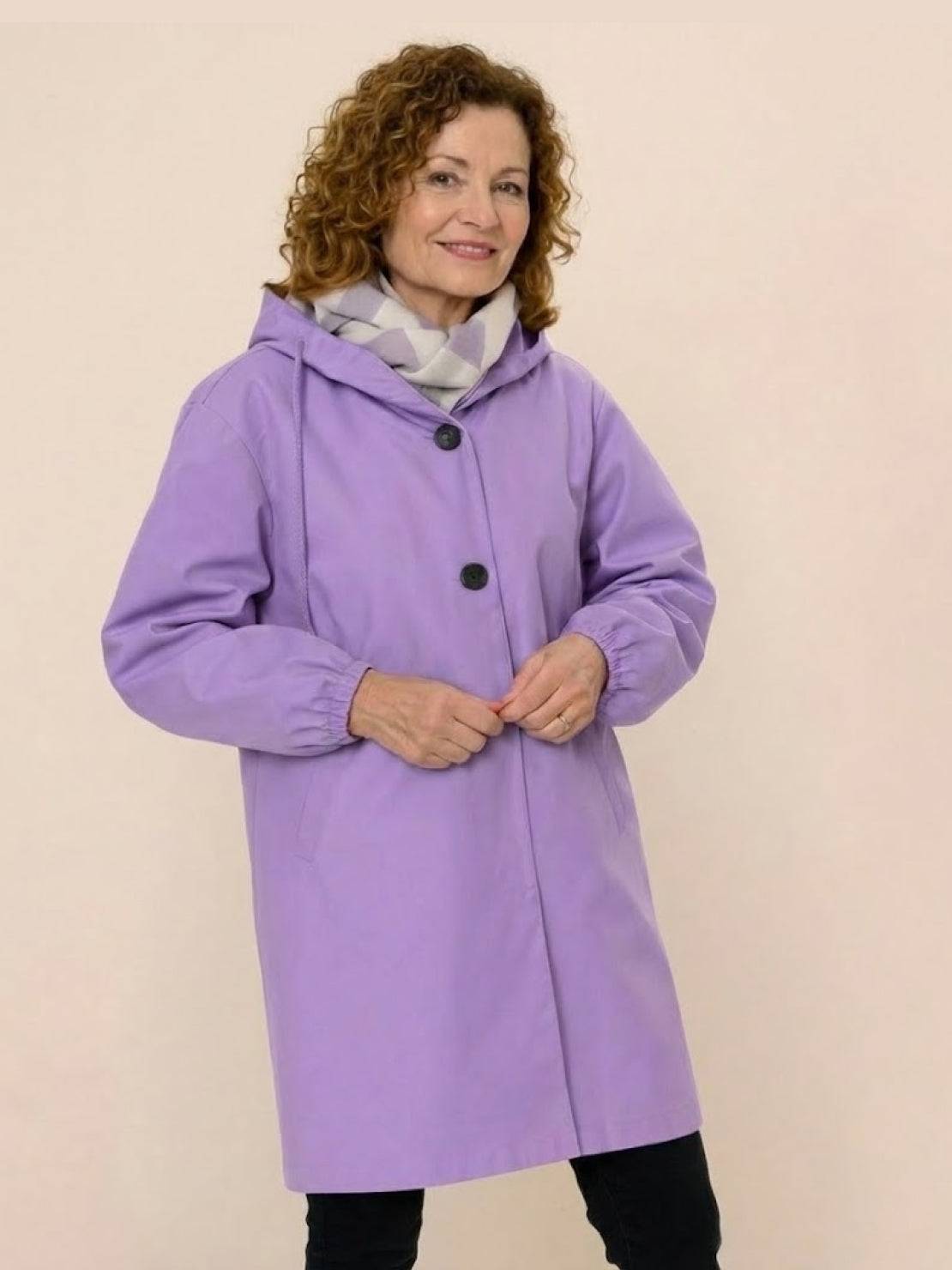 Woman wearing oversized lavender Rain Couture Windbreaker with hood and black buttons