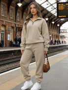 woman wearing beige ultra-soft and comfy co-ord tracksuit set in train station carrying brown handbag