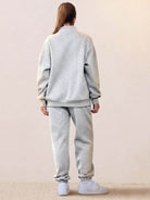 Back view of a woman wearing an ultra-soft and comfy grey co-ord tracksuit set with jogger pants and a zip-up jacket.