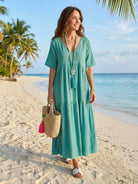 Woman wearing a khaki V-neck two-tiered maxi swing dress with irregular hemline and flowing sleeves