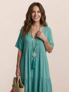Woman wearing a V-neck two-tiered maxi swing dress with irregular hemline and flowy sleeves in a solid color