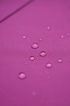 Close-up of water-repellent fabric with water droplets on purple surface for raincoat