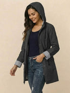 Women wearing a black water resistant hooded striped windbreaker jacket with rolled cuffs and front pockets