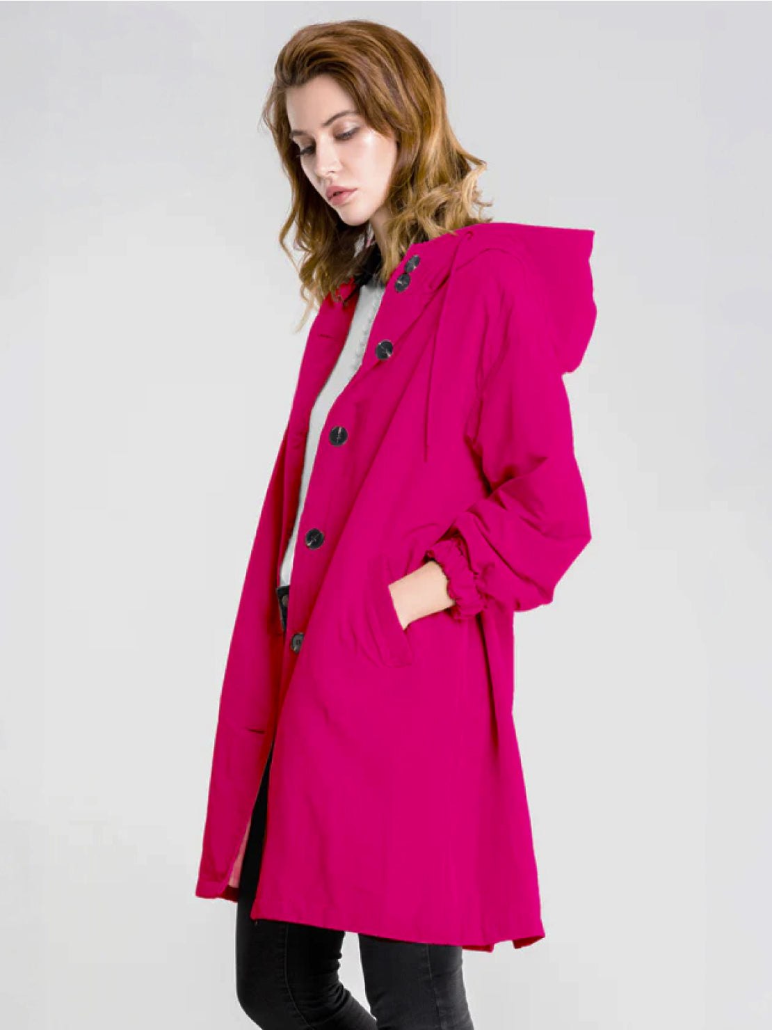 Water-resistant oversized hooded windbreaker rain jacket displayed on model outdoors