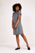 Woman wearing grey short sleeve shift dress with round neck and side pockets, knee-length professional style
