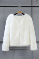 white bold faux fur luxe jacket with V neckline and button front closure hanging on wooden hanger
